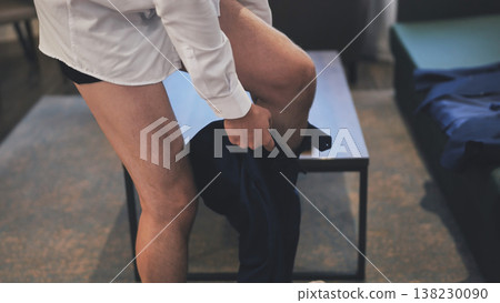 Groom wearing underwear and white shirt putting on his pants while getting ready for his wedding day Groom wearing underwear and white shirt putting on his pants while getting ready for his wedding day 138230090