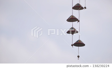 Handmade ceramic wind chime hanging against a soft, overcast sky. Handmade ceramic wind chime hanging against a soft, overcast sky. 138230224