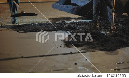 Road construction workers laying fresh asphalt at night, improving city infrastructure Road construction workers laying fresh asphalt at night, improving city infrastructure 138230263