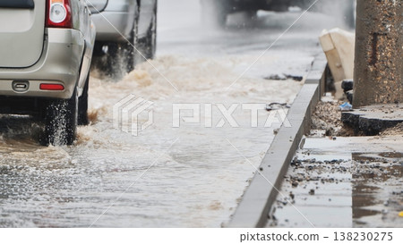 Cars driving through flooded city street, splashing water on a rainy day Cars driving through flooded city street, splashing water on a rainy day 138230275
