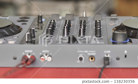 DJ controller with connected cables and knobs for mixing music at an event 138230356