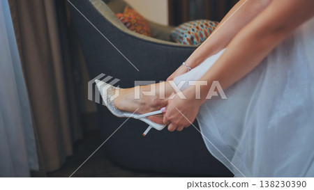 Bride putting on elegant high heel shoes before wedding ceremony. Bride putting on elegant high heel shoes before wedding ceremony. 138230390