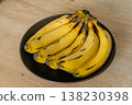 Vivid Scene Of Ripe Banana Cluster Placed On Wooden Surface In Cozy Kitchen Ambiance 138230398