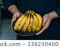 Banana Energy Boost. Man Displays Yellow Bananas With Brown Stems In Kitchen Setting 138230400