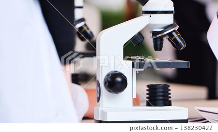 Student viewing microscope in science laboratory experiment 138230422