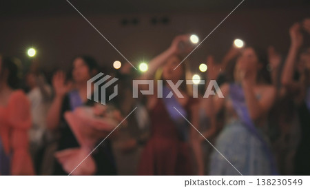 Graduates waving flashlights during commencement ceremony, celebrating their academic achievement with flowers and sashes Graduates waving flashlights during commencement ceremony, celebrating their academic achievement with flowers and sashes 138230549
