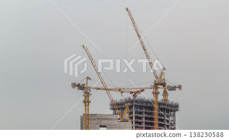 Aerial view of a skyscraper under construction with huge cranes timelapse in Dubai marina. Aerial view of a skyscraper under construction with huge cranes timelapse in Dubai marina. 138230588