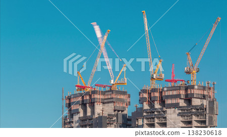 Aerial view of a skyscraper under construction with huge cranes timelapse in Dubai marina. Aerial view of a skyscraper under construction with huge cranes timelapse in Dubai marina. 138230618