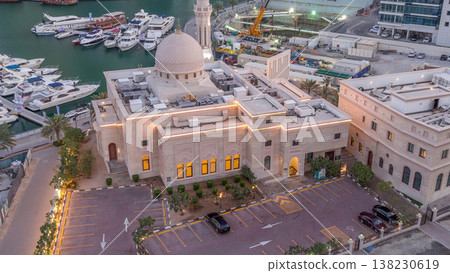 Yachts in Dubai Marina flanked by the Al Rahim Mosque and residential towers and skyscrapers aerial night to day timelapse. Yachts in Dubai Marina flanked by the Al Rahim Mosque and residential towers and skyscrapers aerial night to day timelapse. 138230619