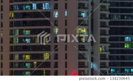 Rows of glowing windows with people in apartment building at night. Rows of glowing windows with people in apartment building at night. 138230645