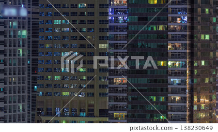 Rows of glowing windows with people in apartment building at night. Rows of glowing windows with people in apartment building at night. 138230649