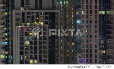 Windows of the multi-storey building with lighting inside and moving people in apartments timelapse. Windows of the multi-storey building with lighting inside and moving people in apartments timelapse. 138230856