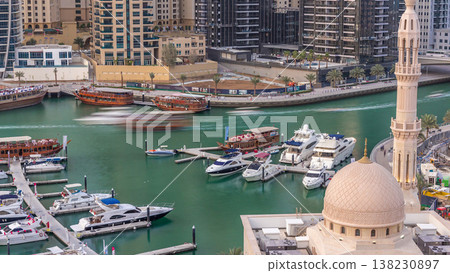 Yachts in Dubai Marina flanked by the Al Rahim Mosque and residential towers and skyscrapers aerial timelapse. Yachts in Dubai Marina flanked by the Al Rahim Mosque and residential towers and skyscrapers aerial timelapse. 138230897