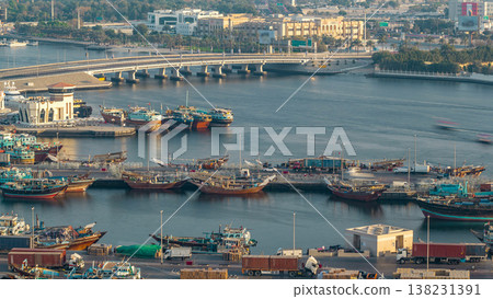 Dubai creek landscape timelapse with boats and ship in port and modern buildings in the background during sunset Dubai creek landscape timelapse with boats and ship in port and modern buildings in the background during sunset 138231391