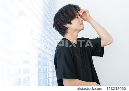 A young man styling his hair by the window. A young man styling his hair by the window. 138232060