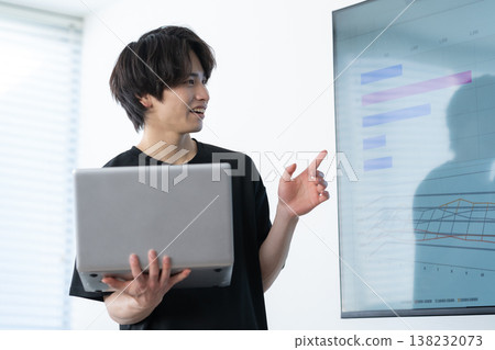 A young man working on a computer in an office. A young man working on a computer in an office. 138232073