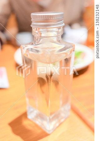 A photograph of a small bottle of sake placed on a table. A photograph of a small bottle of sake placed on a table. 138232148