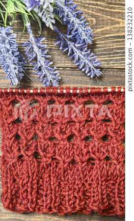 A relief openwork pattern knitted with colored yarn on a wooden background A relief openwork pattern knitted with colored yarn on a wooden background 138232210