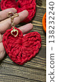 Red knitted heart-shaped keychain on a wooden background. Handmade. 138232240