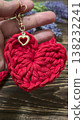 Red knitted heart-shaped keychain on a wooden background. Handmade. 138232241
