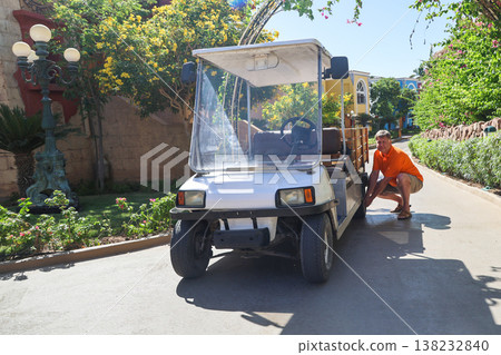 A farmer repairs a wheel on his mini-electric truck, combining modern technology with traditional farming A farmer repairs a wheel on his mini-electric truck, combining modern technology with traditional farming 138232840