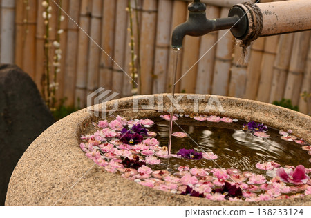 A beautiful Japanese tranquil space with a flower-filled water basin and flowing water. A beautiful Japanese tranquil space with a flower-filled water basin and flowing water. 138233124