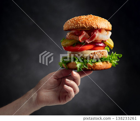 Hand holds out a fresh tasty hamburger. 138233261