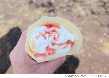 Strawberry whipped cream crepes on hand, perfect for eating on the go as an outdoor dessert ingredient. 138233417