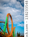 Low angle view of a vibrant orange roller coaster loop and green supports under a dramatic sky 138233548