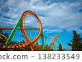 Wide shot of a green and orange roller coaster structure with a radio tower in the background 138233549