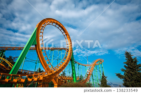 Wide shot of a green and orange roller coaster structure with a radio tower in the background Wide shot of a green and orange roller coaster structure with a radio tower in the background 138233549