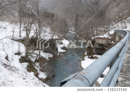 The Nishine River flows through a snow-covered valley. 138233588