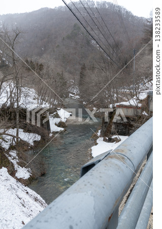 The Nishine River flows through a snow-covered valley. 138233589