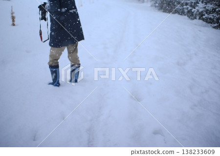 A figure standing on a snowy path with footprints; copy space material conveying winter outdoor activities. A figure standing on a snowy path with footprints; copy space material conveying winter outdoor activities. 138233609