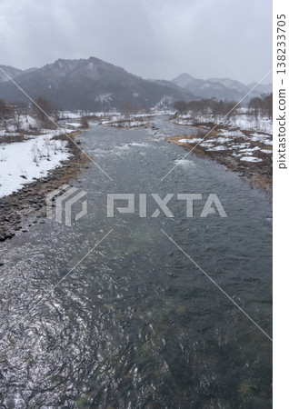 The Inagawa River flowing through Minamiaizu town in winter, and the scenery of snow-covered mountains. 138233705