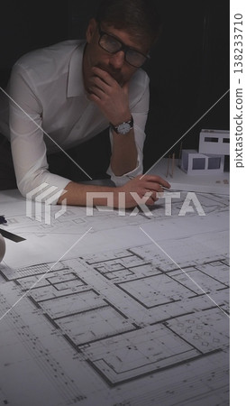 Architect drawing floor plans and looking at a house model, developing construction projects and residential building designs. Concept of architecture and business in low key lighting Architect drawing floor plans and looking at a house model, developing construction projects and residential building designs. Concept of architecture and business in low key lighting 138233710