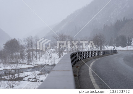 A winter scene overlooking the hazy mountains of Minami-Aizu and the Inagawa River as snow falls. 138233752
