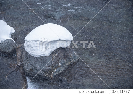 Snow-capped rocks in a mountain stream; a winter scene of snow falling on the Inagawa River in Hinoemata Village and the calm surface of the water. Snow-capped rocks in a mountain stream; a winter scene of snow falling on the Inagawa River in Hinoemata Village and the calm surface of the water. 138233757