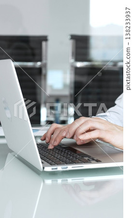 Hands expertly typing on a laptop keyboard, a professional working on important business tasks and digital communication in a modern, clean office environment 138233937