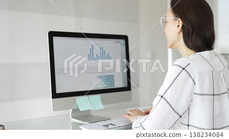 Businesswoman at glass office desk analyzing charts and graphs on computer screen, reviewing financial reports and performance data for planning. Business people concept Businesswoman at glass office desk analyzing charts and graphs on computer screen, reviewing financial reports and performance data for planning. Business people concept 138234084