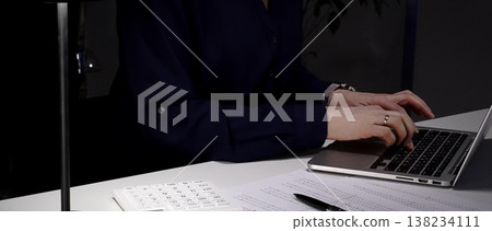 Woman's hands typing on laptop at office desk, working late night with calculator and financial documents. Audit and taxes in business Woman's hands typing on laptop at office desk, working late night with calculator and financial documents. Audit and taxes in business 138234111