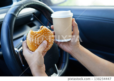 Asian woman driver hold and eat hamburger food in car. Asian woman driver hold and eat hamburger food in car. 138234447