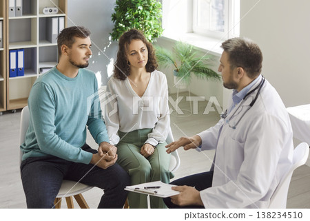 Doctor explaining diagnosis and treatment, health news to couple of patients in hospital office Doctor explaining diagnosis and treatment, health news to couple of patients in hospital office 138234510