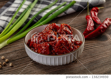 Spicy red chili pickle in a white bowl on a rustic wooden table with fresh ingredients Spicy red chili pickle in a white bowl on a rustic wooden table with fresh ingredients 138234930