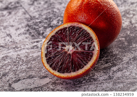 Fresh ripe blood orange, whole and sliced in half on a textured surface. Fresh ripe blood orange, whole and sliced in half on a textured surface. 138234959