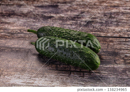 Two fresh green pickling cucumbers on a rustic dark wood background. Two fresh green pickling cucumbers on a rustic dark wood background. 138234965