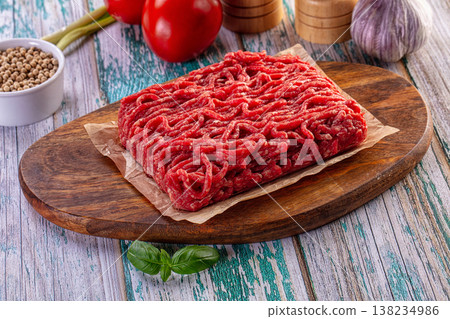 Fresh minced beef on a rustic wooden board with tomatoes, garlic and herbs for cooking. Fresh minced beef on a rustic wooden board with tomatoes, garlic and herbs for cooking. 138234986