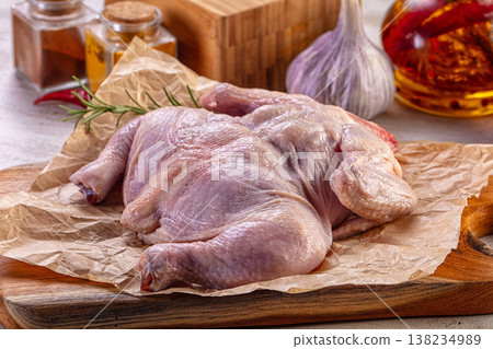 Raw spatchcocked chicken on a wooden cutting board with fresh ingredients for cooking. Raw spatchcocked chicken on a wooden cutting board with fresh ingredients for cooking. 138234989