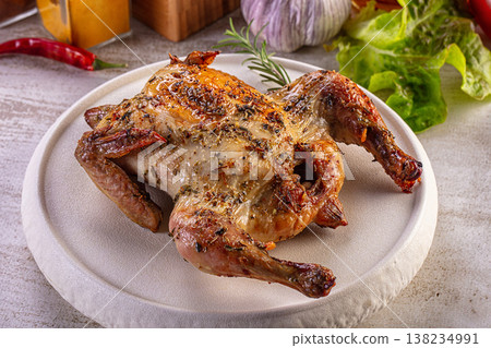 Gourmet roasted quail with herbs on a white plate, surrounded by fresh vegetables and spices. Gourmet roasted quail with herbs on a white plate, surrounded by fresh vegetables and spices. 138234991