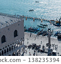 Sunlit Venetian waterfront with gondolas and tourists 138235394